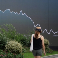 A pedestrian near a giant display showing a stock graph, in Shanghai on Aug. 3.  | REUTERS