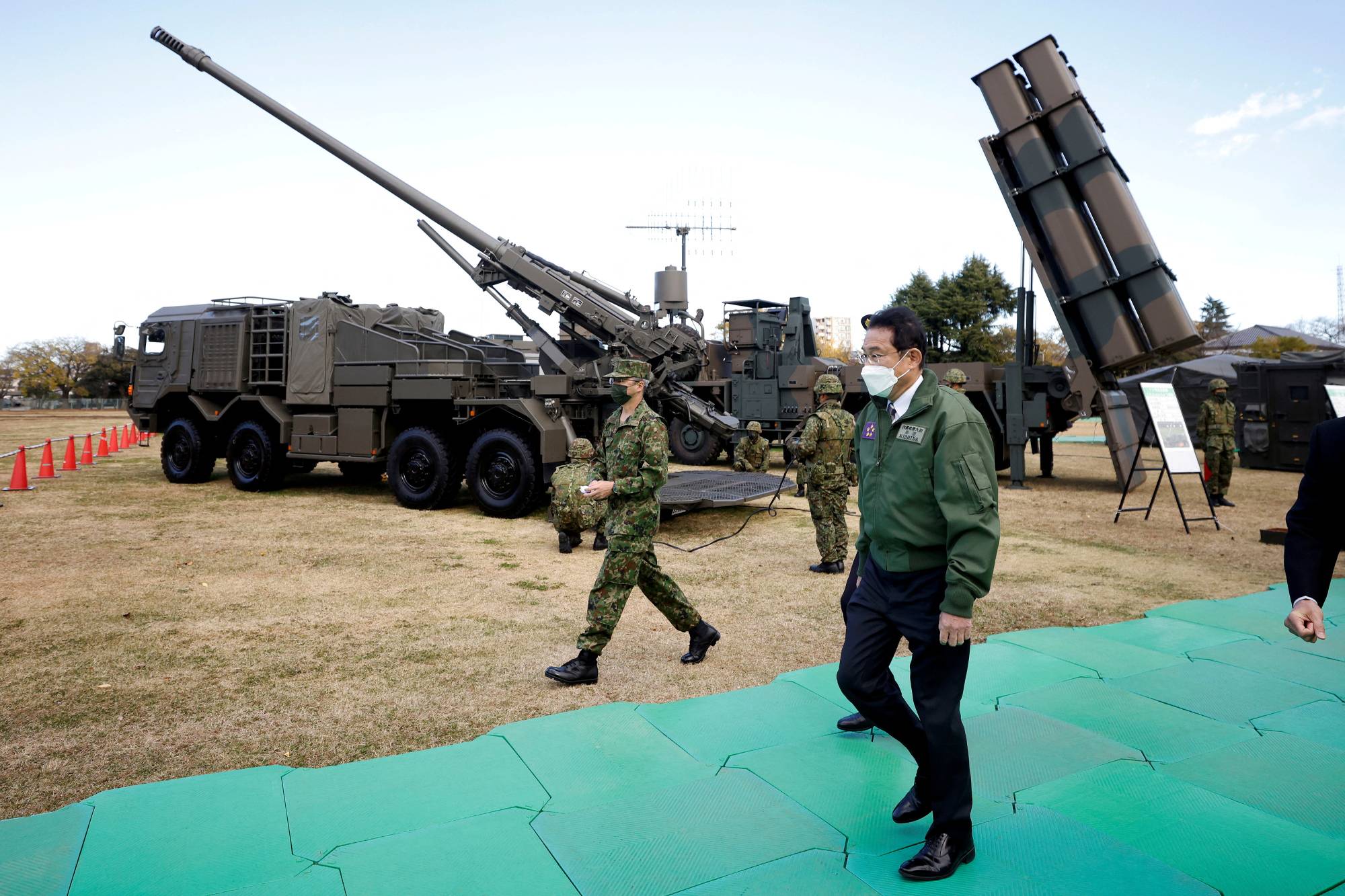 Prime Minister Fumio Kishida walks past a Ground Self-Defense Force Type-19 155 mm wheeled self-propelled howitzer and a Type-12 surface-to-ship missile during a review at Camp Asaka in Tokyo in November. | POOL / VIA REUTERS