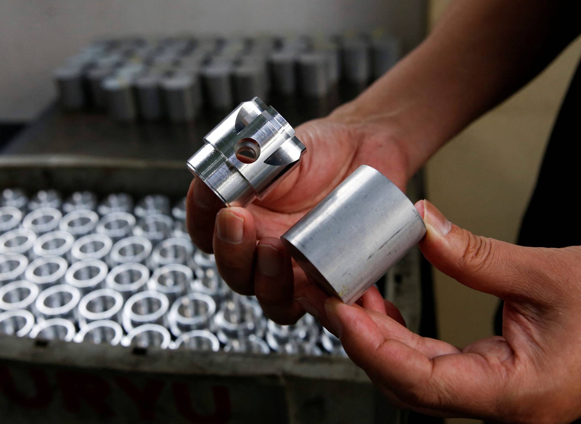Hirotomi Kojima, CEO of Katsui Kogyo, holds components made at his factory in Higashiosaka, on June 23. | Reuters