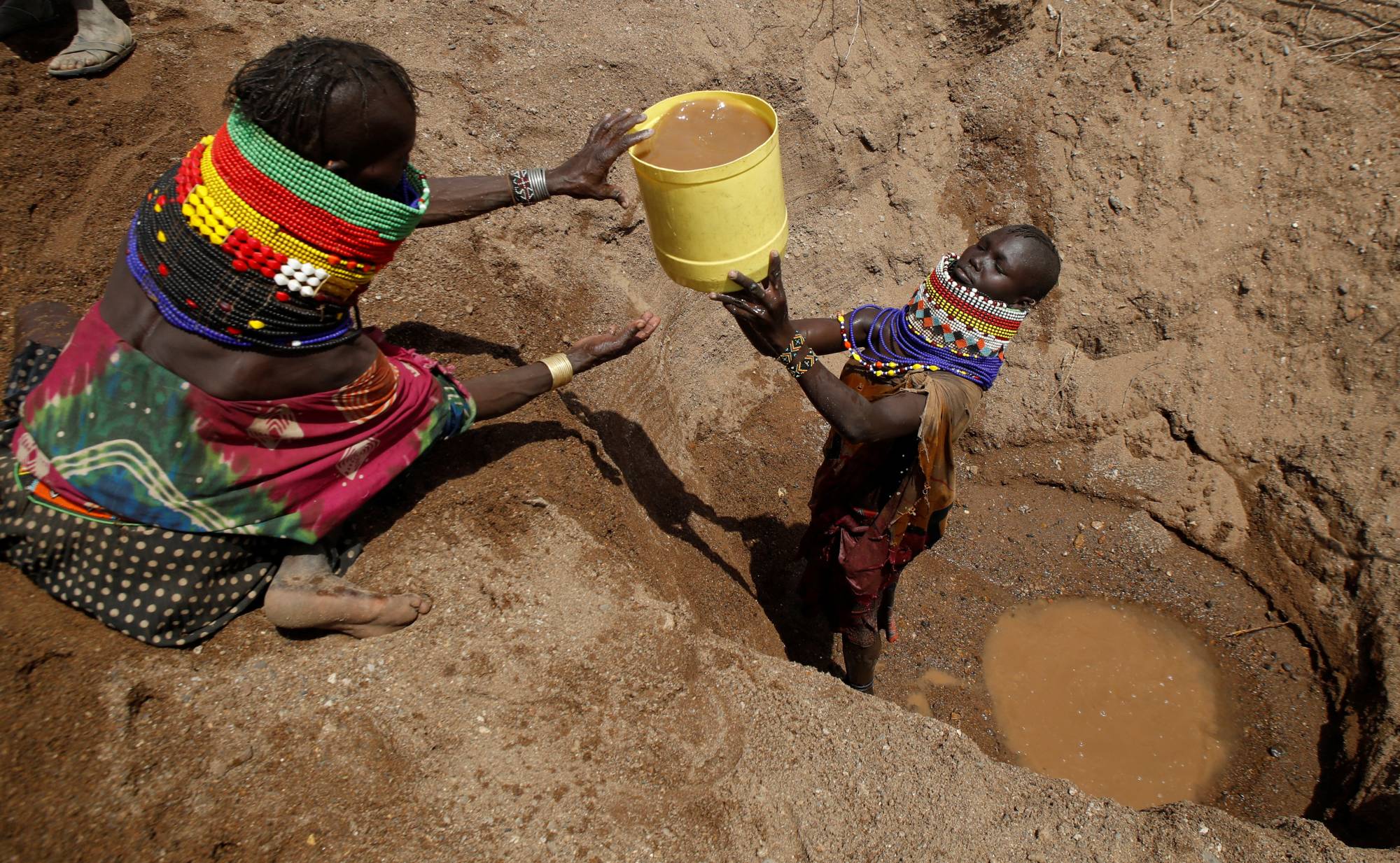 Turkana tribe women fetch water for their goats from a shallow well near Lorengo village, Kenya, on July 19. | REUTERS