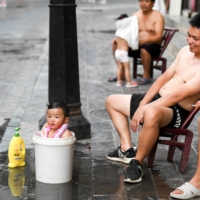 A child bathes in a bucket to cool off amid a heat wave warning in Huayuan county, in China\'s Hunan province, on Aug. 15. | CNSPHOTO / VIA REUTERS   