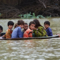 A man and a youth use a satellite dish to move children across a flooded area after heavy monsoon rainfalls in the Jaffarabad district of Pakistan\'s Balochistan province on Friday. | AFP-JIJI