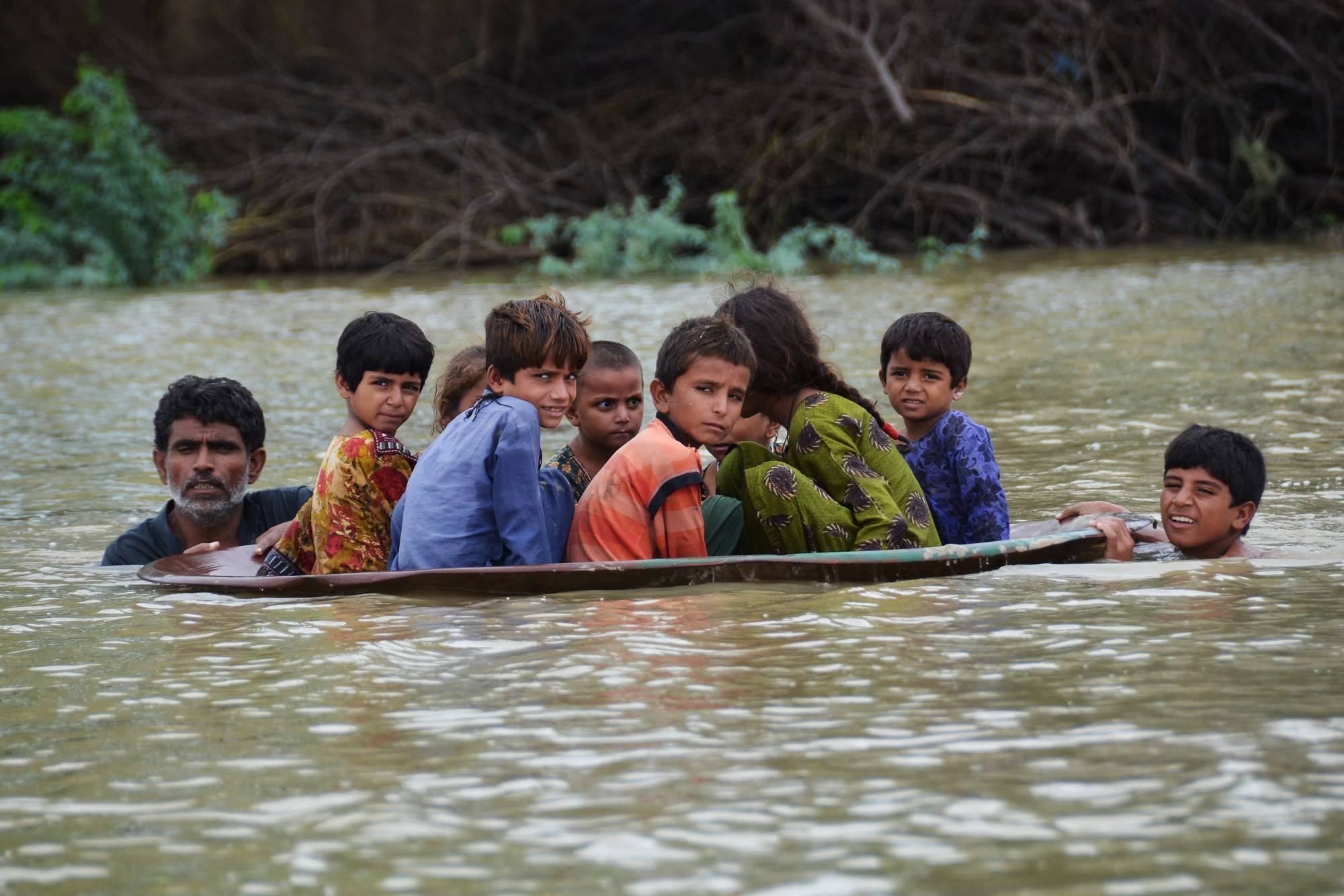 A man and a youth use a satellite dish to move children across a flooded area after heavy monsoon rainfalls in the Jaffarabad district of Pakistan's Balochistan province on Friday. | AFP-Jiji