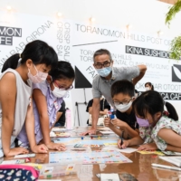 Children play a board game intended to familiarize them with the United Nations’ Sustainable Development Goals campaign in Tokyo on Aug. 17. | NORIKO HAYASHI / THE NEW YORK TIMES