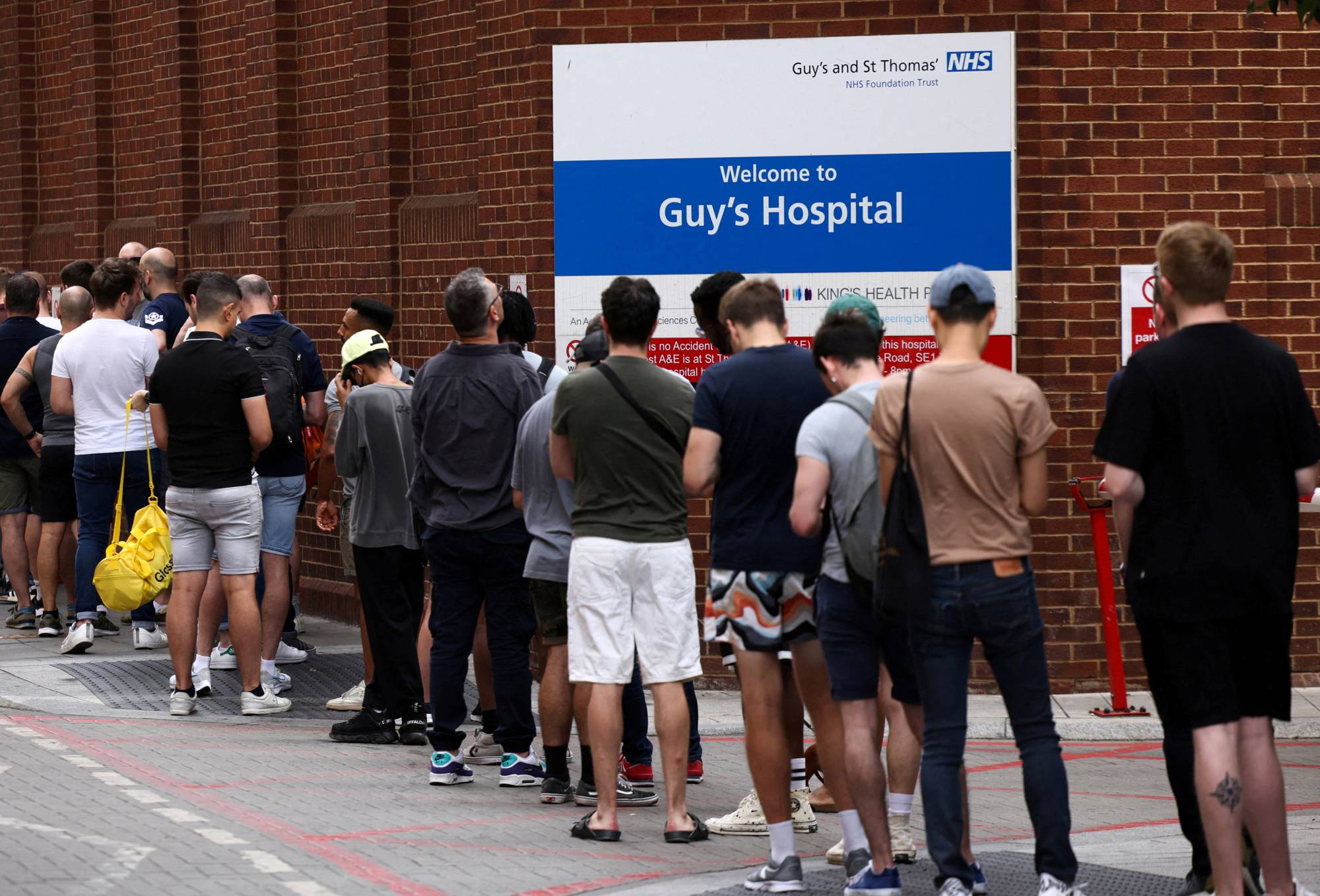 People line up to receive monkeypox vaccinations during a pop-up clinic at Guy's Hospital in central London on July 30. | REUTERS