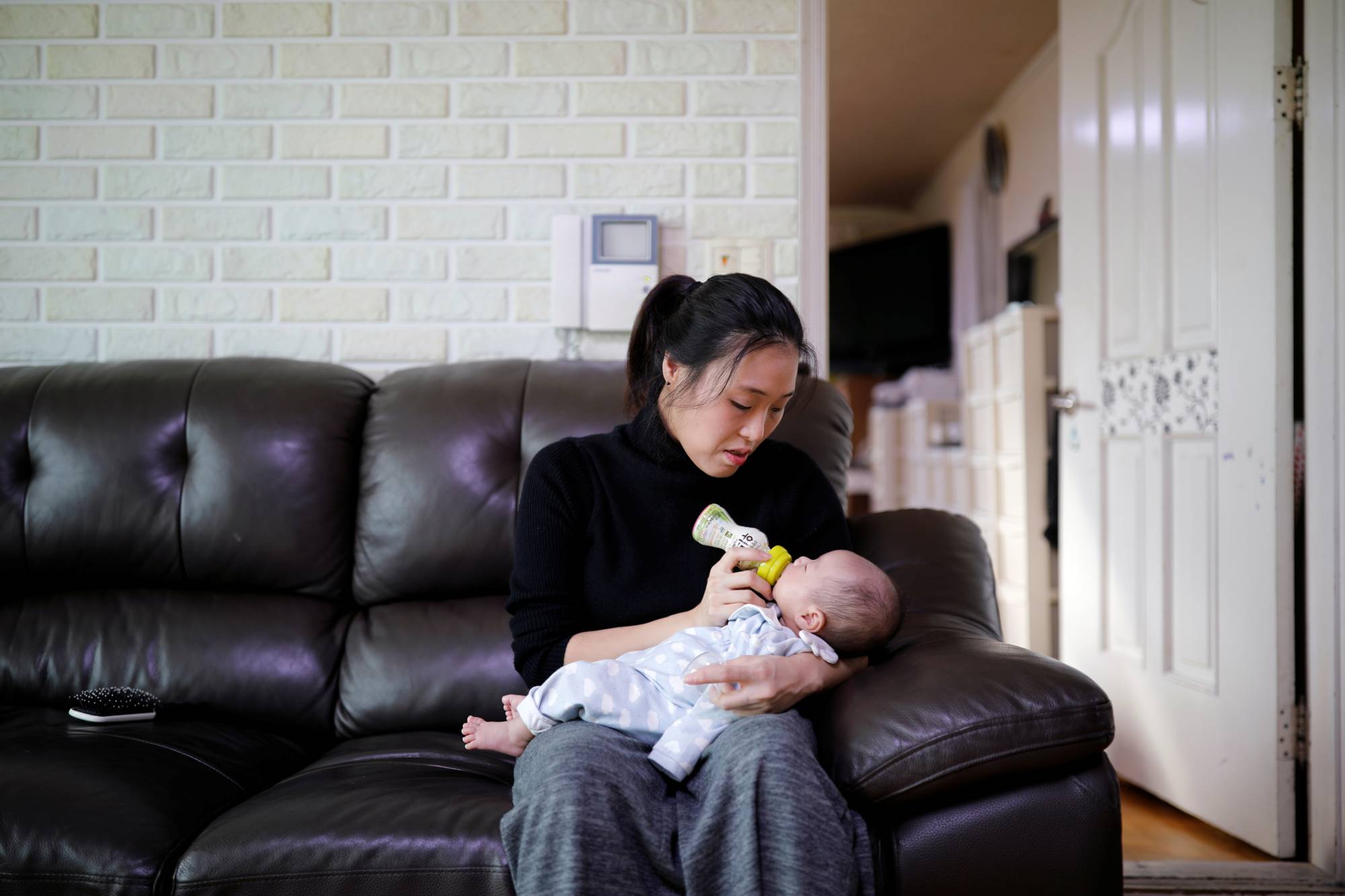 Korean mother Kim Mi-sung feeds her infant son at their home in Seoul in 2018. | REUTER
