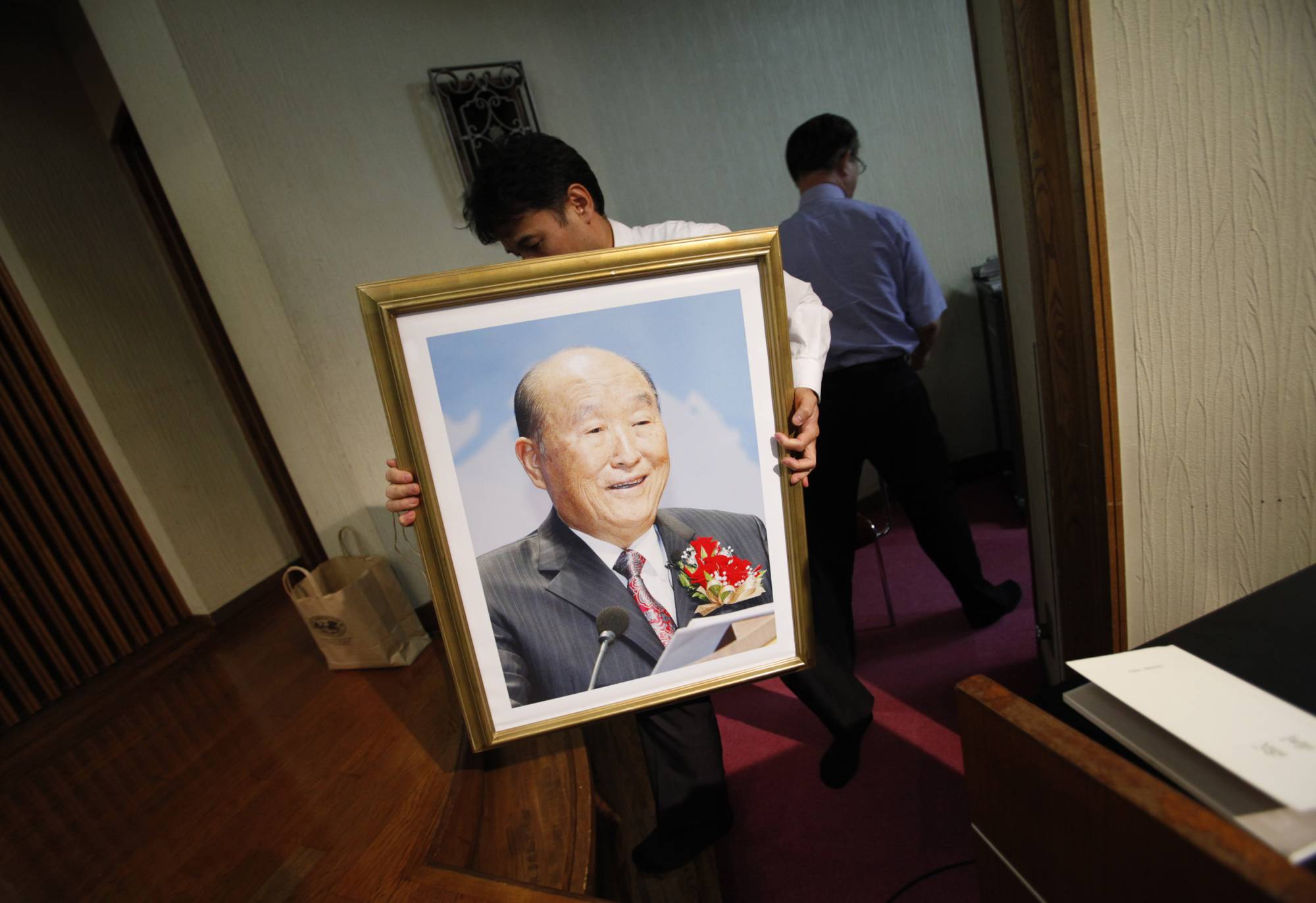 A believer carries a portrait of Unification Church founder Sun Myung Moon toward an altar during a memorial Mass at the church's Japan headquarters in Tokyo on Sept. 3, 2012. | REUTERS