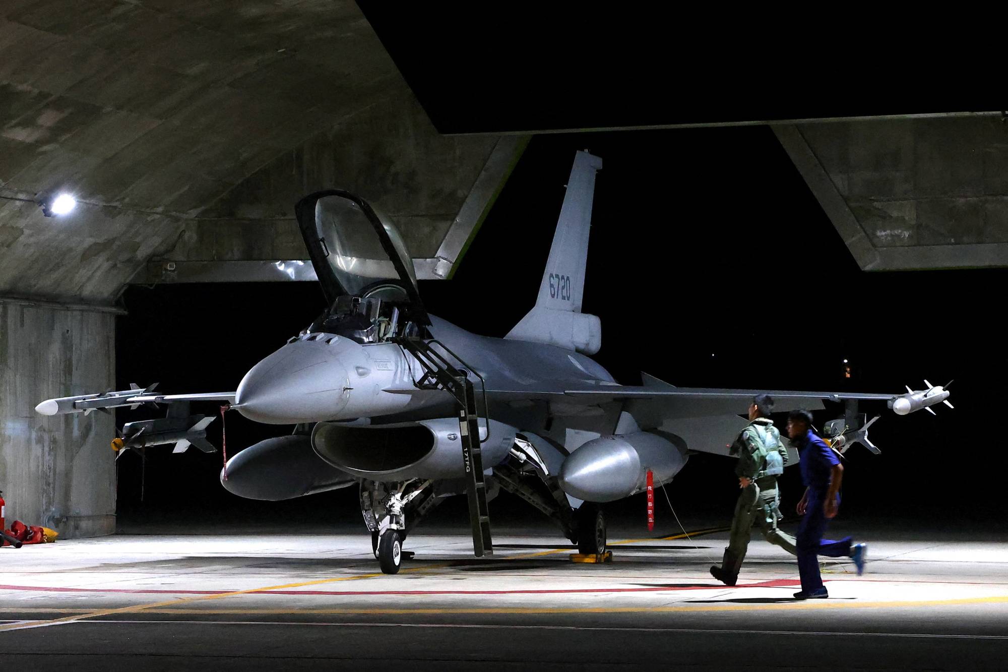 A Taiwanese pilot runs toward an F-16V fighter jet for an evening takeoff as part of a combat readiness mission at the airbase in Hualien, Taiwan, on Aug. 17. | REUTERS