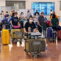 Passengers arrive at Tokyo\'s Haneda Airport on Wednesday morning. Starting Wednesday, travelers don\'t need to take pre-arrival PCR tests as part of eased border restrictions. | KYODO