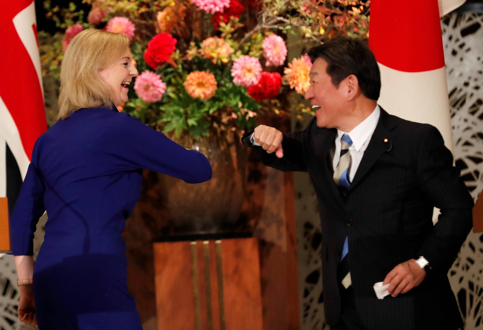 Then-international trade minister Liz Truss and then-Foreign Minister Toshimitsu Motegi bump elbows following a signing ceremony for the U.K.-Japan Comprehensive Economic Partnership Agreement in Tokyo in October, 2020. | REUTERS