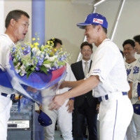 Dragons outfielder Kosuke Fukudome (left) receives flowers from teammates Yohei Oshima after announcing his retirement in Nagoya on Thursday. | KYODO