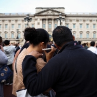 People outside Buckingham Palace listen as King Charles III addresses the nation. | REUTERS