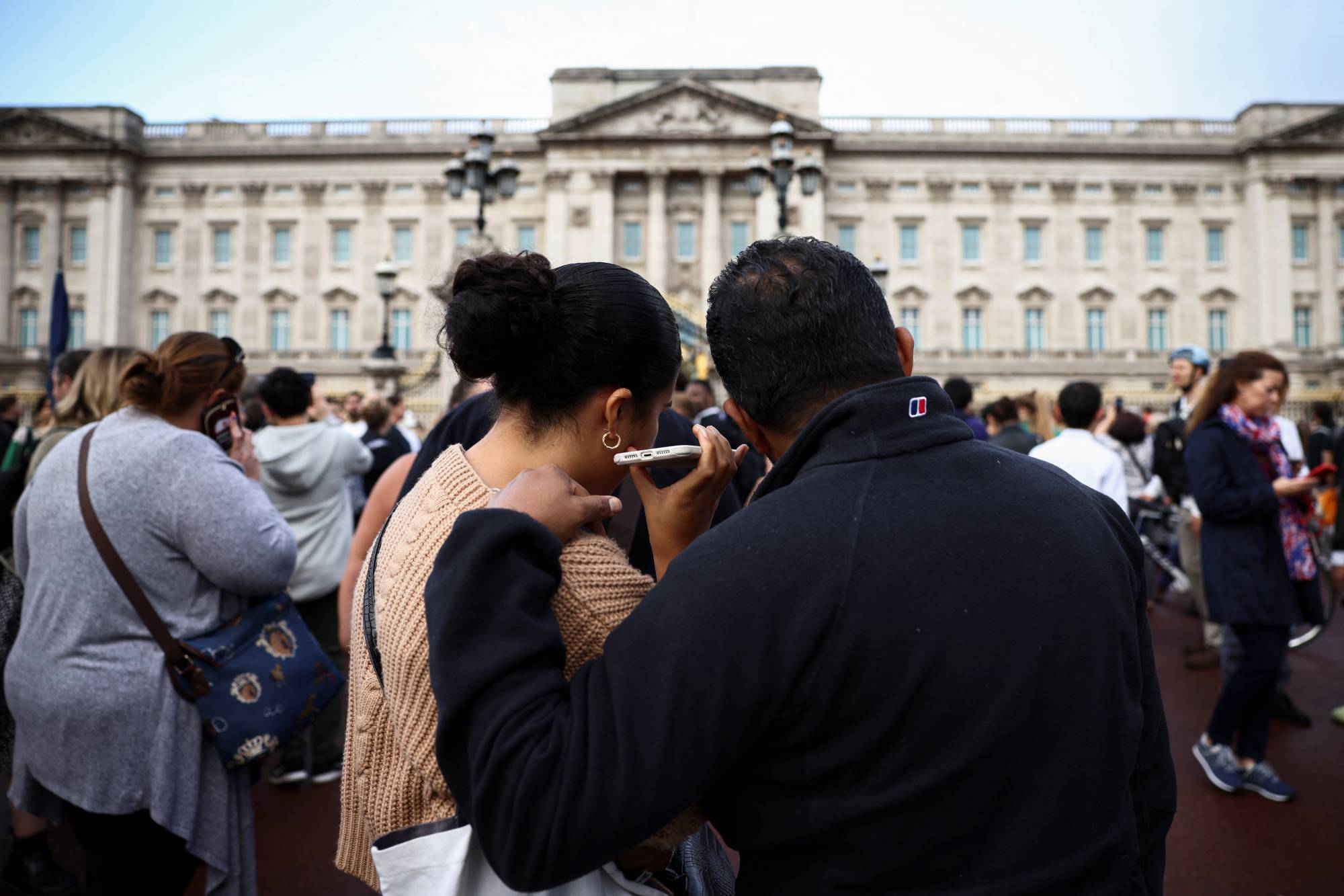 People outside Buckingham Palace listen as King Charles III addresses the nation. | Reuters