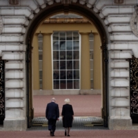 King Charles III and Queen Camilla walk into Buckingham Palace on Friday.  | REUTERS