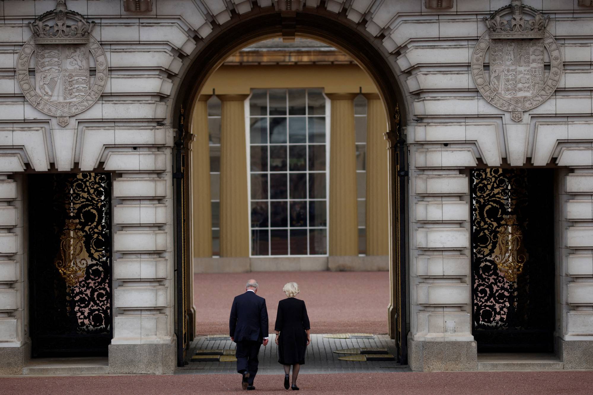 King Charles III and Queen Camilla walk into Buckingham Palace on Friday. | Reuters