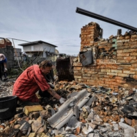 Volunteers clear the rubble of a destroyed house as a result of shelling in village of Moshchun, Kyiv region, on Friday.  | AFP-JIJI