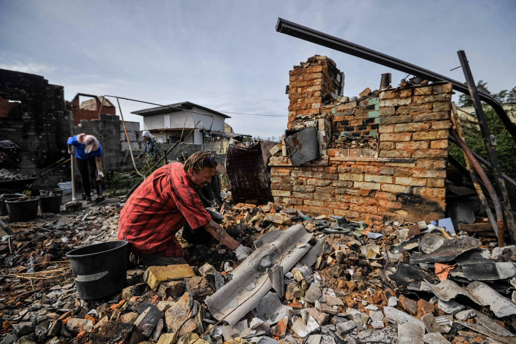 Volunteers clear the rubble of a destroyed house as a result of shelling in village of Moshchun, Kyiv region, on Friday. | AFP-JIJI