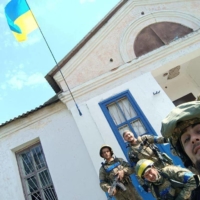 Ukrainian soldiers pose with their country\'s national flag in the village of Vasylenkove on Saturday. The area was recently liberated from the Russians after Ukrainian forces launched a counteroffensive in the Kharkiv region.
 | PRESS SERVICE OF THE TERRITORIAL DEFENCE OF THE UKRAINIAN ARMED FORCES / VIA REUTERS  