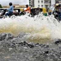 Traffic moves as water is pumped out of an inundated residential area following torrential rains in Bengaluru on Sept. 7. | REUTERS 