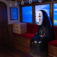 The character No-Face, from the 2001 film \"Spirited Away,\" sits in a train in at Ghibli Park in Aichi Prefecture. | COURTESY OF 2001 STUDIO GHIBLI・NDDTM / VIA KYODO