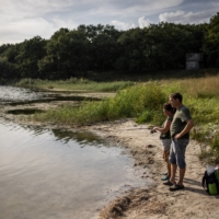 Alex Khainus, a supporter of Ukraine in a region with many separatists and Russian sympathizers, with a friend fishing on a pond in Chasiv Yar, Ukraine, on Aug. 25.  | JIM HUYLEBROEK / THE NEW YORK TIMES