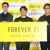 Adastria President Osamu Kimura (center) holds a Forever 21 banner at a news conference in Tokyo on Wednesday. | KYODO
