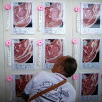 A man inspects images of award-winning carcasses of beef at the \"Wagyu Olympics\" in 2017. | REUTERS