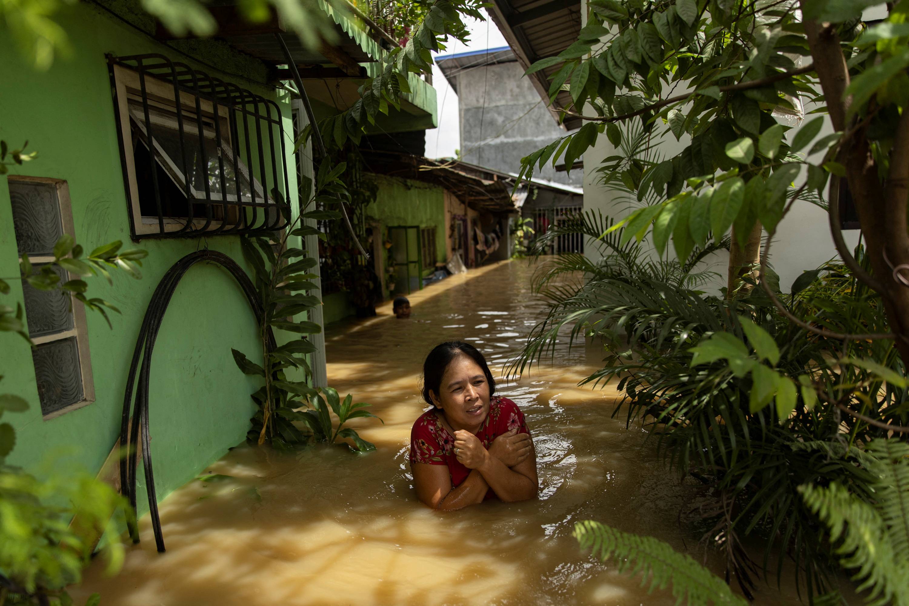 A woman wades through chest-deep flood water after Super Typhoon Noru, in San Ildefonso, Bulacan province, Philippines, on Monday. | REUTERS