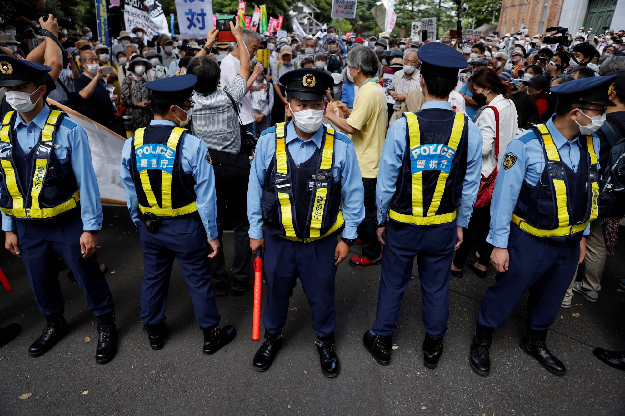 Police officers stand guard during a protest against the state funeral for Abe in Tokyo on Tuesday. | REUTERS