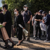 People line up along a street near Nippon Budokan to leave flowers and sign a condolence book ahead of the state funeral for former Prime Minister Shinzo Abe. | AFP-JIJI