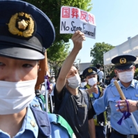 A protester is surronded by police near the Nippon Budokan ahead of the state funeral | AFP-JIJI