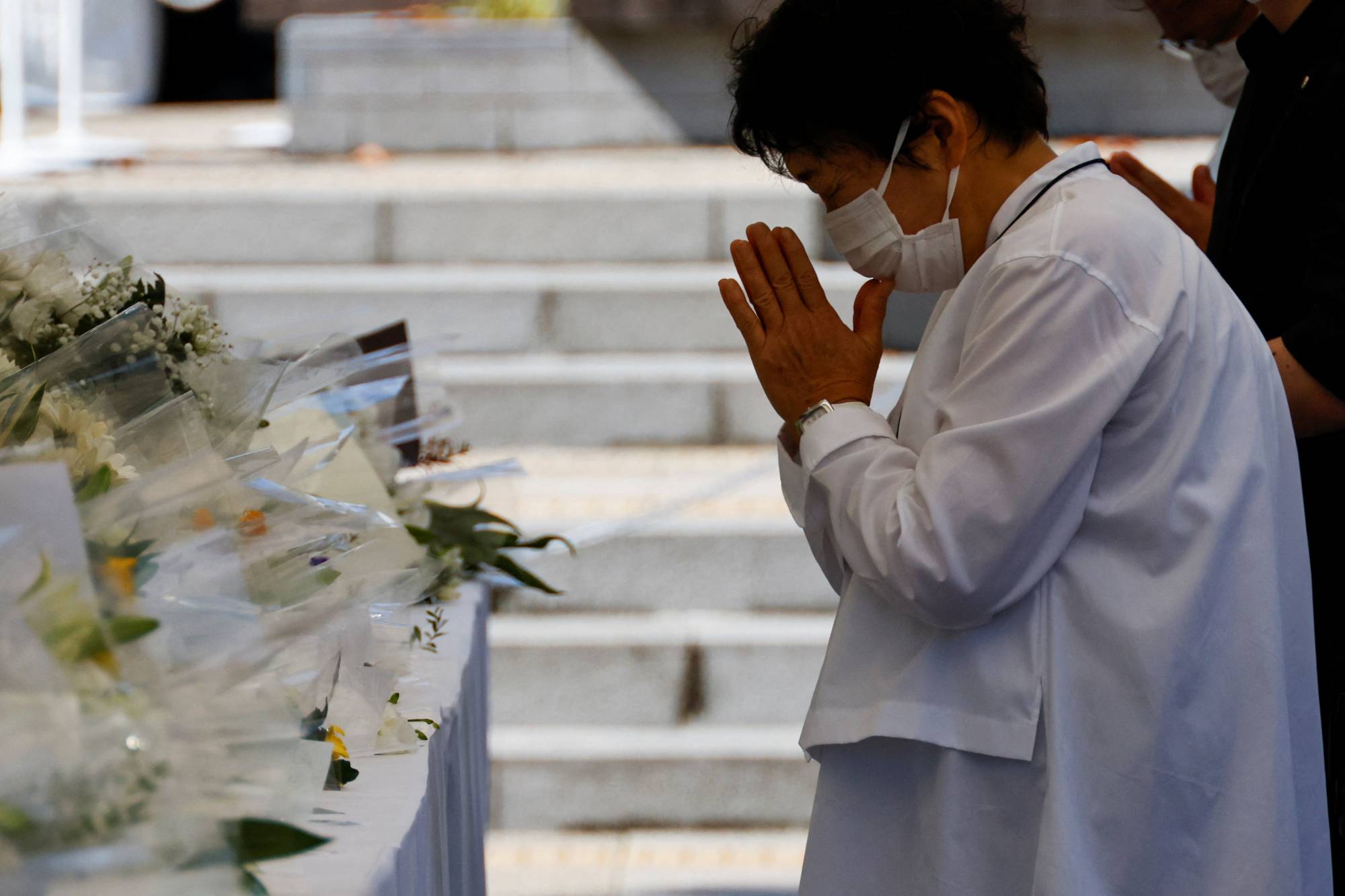 A visitor prays in front of the altar outside the Budokan | REUTERS