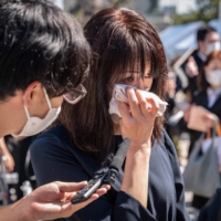 A woman cries during an interview near the funeral venue | AFP-JIJI