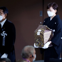 Akie Abe carries the urn containing her husband\'s ashes, as she walks behind Prime Minister Fumio Kishida. | POOL / VIA REUTERS