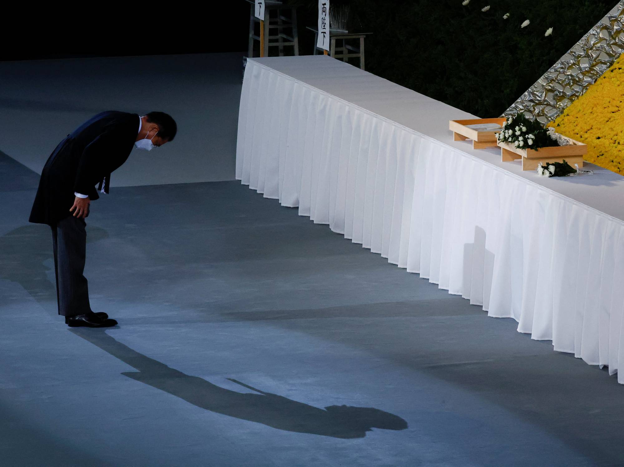 Prime Minister Fumio Kishida bows after laying flowers on the funeral altar. | POOL / VIA REUTERS