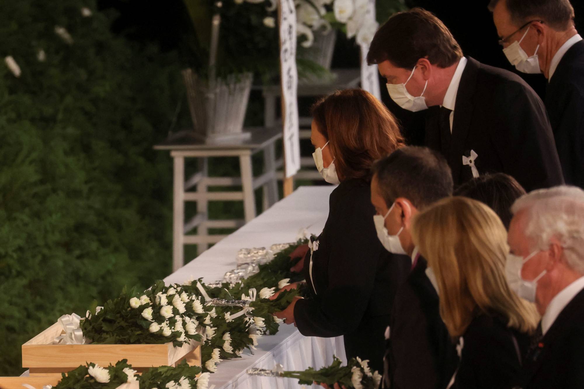 U.S. Vice President Kamala Harris and other officials place flowers in front of the funeral altar | POOL / VIA REUTERS