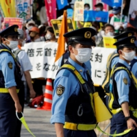 Police officers stand guard as protesters rally outside the parliament building in Nagatacho. | REUTERS
