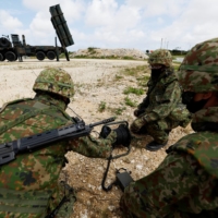 Ground Self-Defense Force members conduct a military drill next to an anti-ship missile unit on Miyako Island, Okinawa Prefecture, in April. | REUTERS
