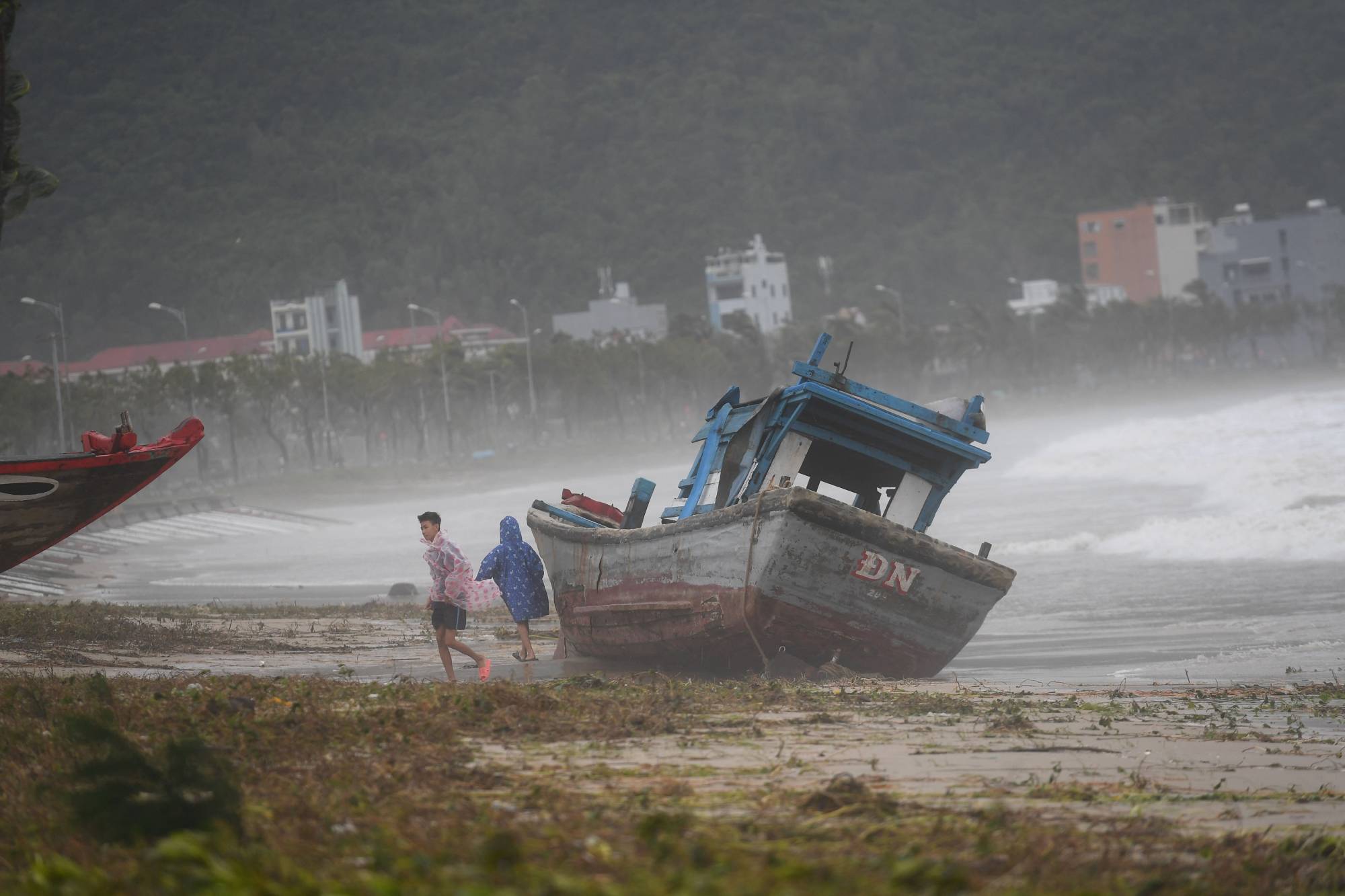 Children play next to a beached boat following the passage of typhoon Noru in Danang, Vietnam, on Wednesday. | AFP-JIJI