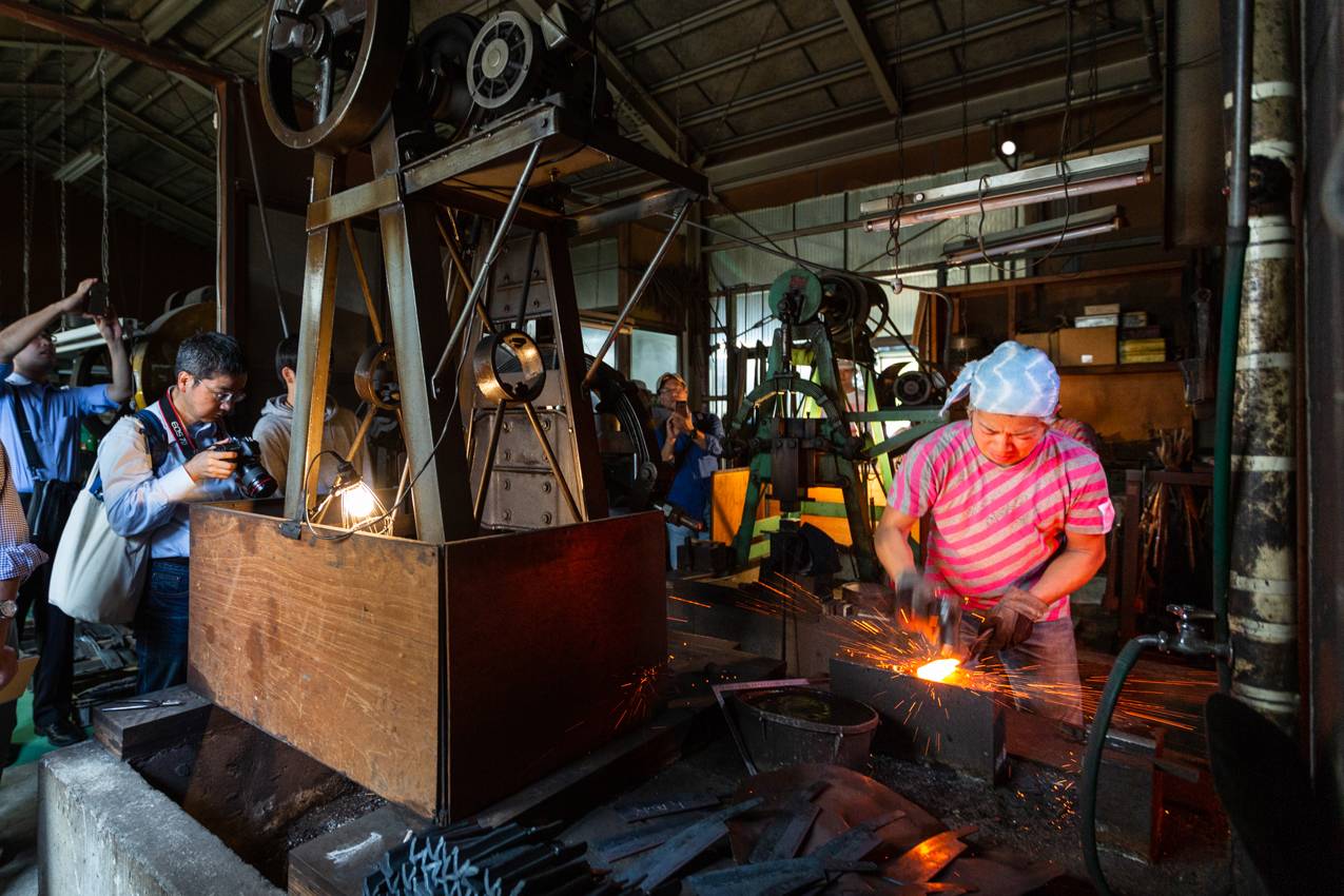 Visitors to the Tsubame-Sanjo Factory Festival in Niigata Prefecture watch a knife-maker forge a blade at Hinoura Hamono. | TSUBAME-SANJO FACTORY FESTIVAL COMMITTEE