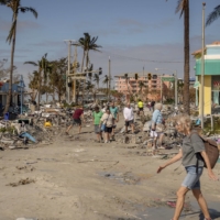 Residents assess the damage from Hurricane Ian in Fort Myers Beach on Thursday.  | HILARY SWIFT / THE NEW YORK TIMES