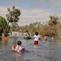 Children play in floodwater after Hurricane Ian passed through Fort Myers on Thursday. | HILARY SWIFT / THE NEW YORK TIMES