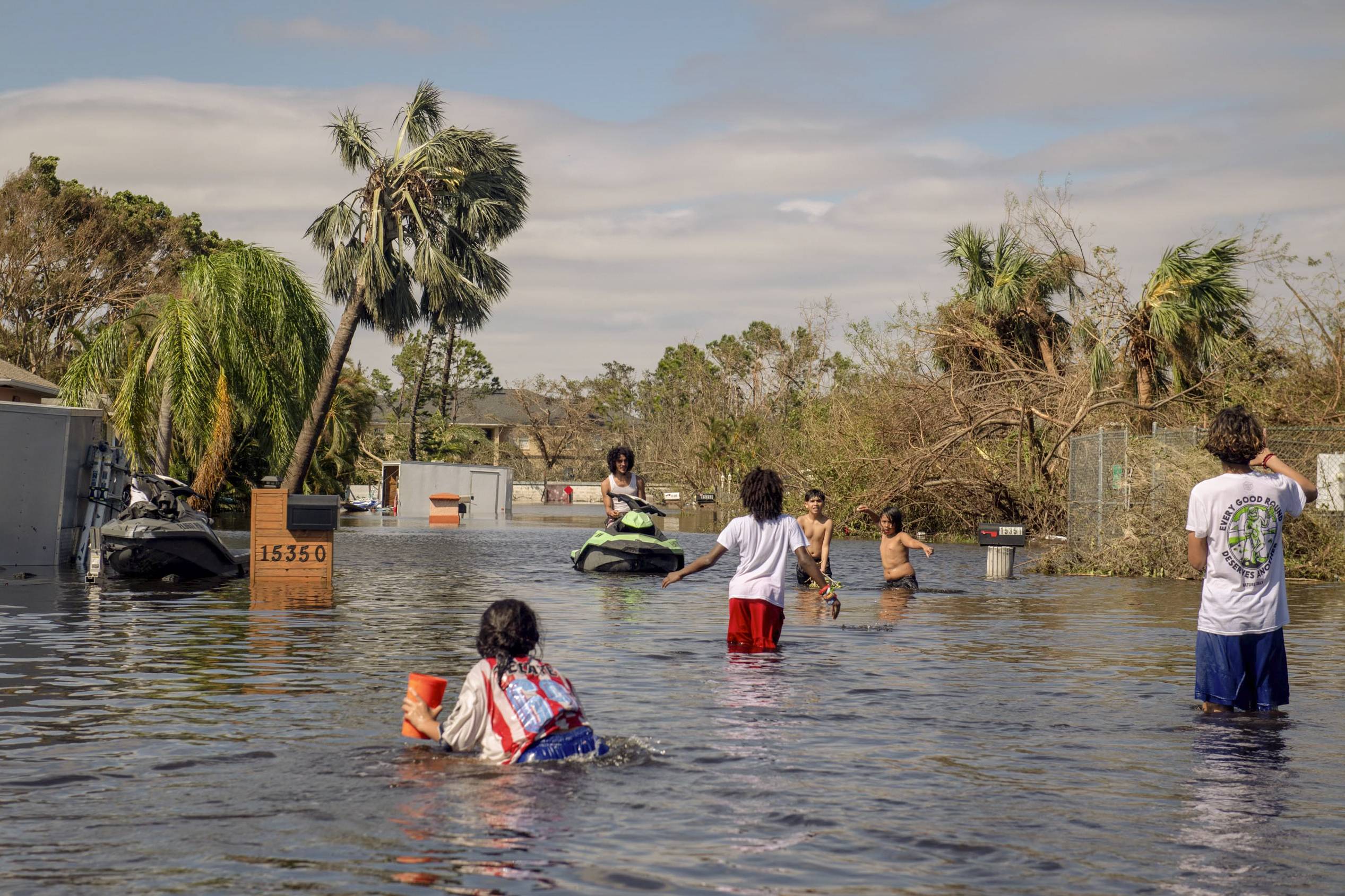 Children play in floodwater after Hurricane Ian passed through Fort Myers on Thursday. | Hilary Swift / The New York Times