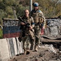 Ukrainian servicemen cross a destroyed bridge over the Oskil River in Kupiansk, eastern Ukraine, on Thursday. 

  | AFP-JIJI