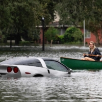 People paddle by in a canoe next to a submerged Chevy Corvette in the aftermath of Hurricane Ian in Orlando, Florida, on Thursday. | AFP-JIJI