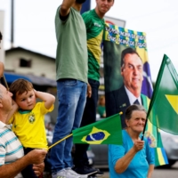 Supporters wave flags as Brazil\'s president and candidate for re-election, Jair Bolsonaro, leads a motorcade in Joinville on Saturday. | REUTERS 
