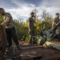 Ukrainian soldiers check for salvageable parts on destroyed and abandoned Russian military vehicles in Izium, Ukraine, on Saturday.  | IVOR PRICKETT / THE NEW YORK TIMES