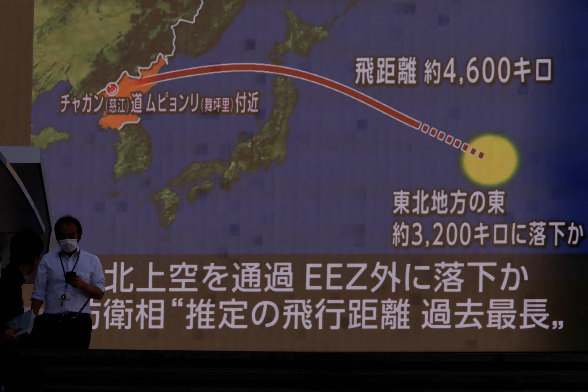 People walk in front of a giant TV screen showing a news report about North Korea's ballistic missile launch over Japan, in Tokyo, on Tuesday. | REUTERS