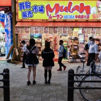 Pedestrians walk past a shop in the popular electronics shopping area of Akihabara in Tokyo on Sept. 21. | AFP-JIJI