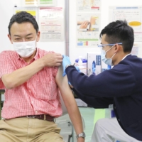 A man gets vaccinated with the omicron-targeted COVID-19 vaccine on Monday in Tokyo. | POOL / VIA KYODO